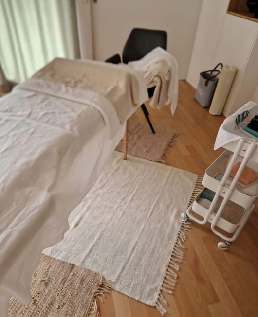 Behandlungsliege mit cremefarbener Decke im ruhigen Raum